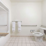 accessible bathroom with toilet, grab bards, shower/tub with seat and towels at Super 8 by Wyndham Fort Worth South