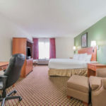 guest suite with plush chair, work desk with rolling chair, one bed, and TV at Super 8 by Wyndham Fort Worth South